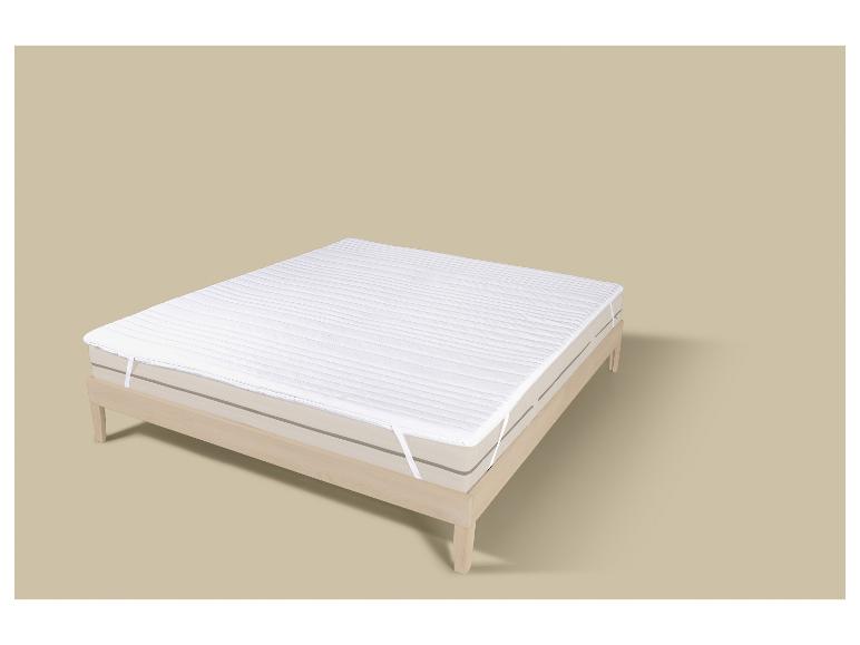 Protège-matelas blanc sur un lit en bois clair