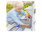 Enfant jouant avec un bac à sable avec robinet et cuisinière.