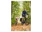 Deux personnes à vélo sur un chemin forestier couvert de feuilles d'automne.