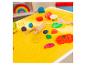 Pâte à modeler colorée et outils de jeu sur un tapis jaune avec motifs alimentaires.