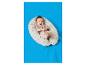 Un bébé souriant en body beige sur un coussin d'allaitement à pois sur une couverture bleue.