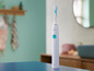 Une brosse à dents électrique Philips Sonicare blanche sur une table bleue.