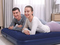 Un couple se trouve sur un matelas pneumatique bleu dans une pièce.
