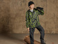 Un garçon porte une veste de camouflage et un pantalon noir et regarde à travers des jumelles.