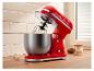 Robot pâtissier rouge avec bol, fouet, œufs et amandes sur un comptoir en bois.