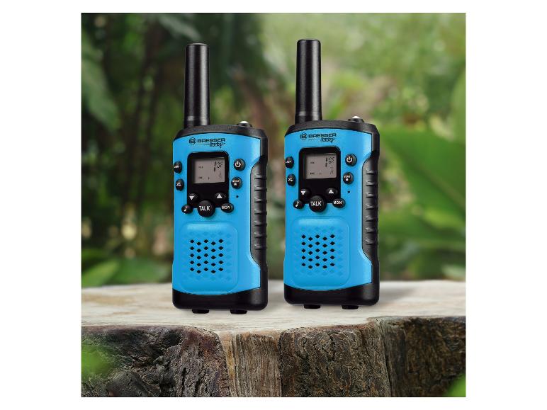 Deux talkies-walkies bleus avec des accents noirs, posés sur une souche d'arbre en extérieur.