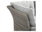 Détail d'un fauteuil en osier gris avec des coussins gris.