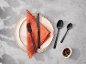 Couverts noirs sur une assiette avec une serviette orange.