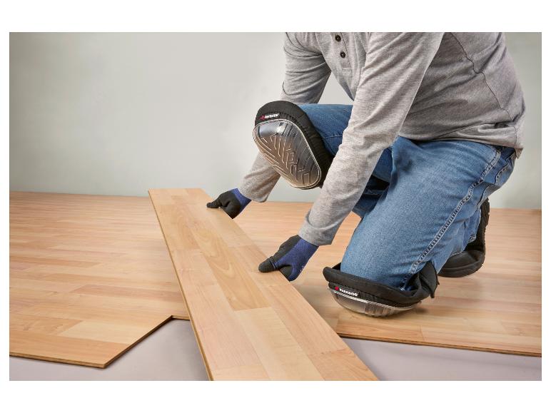 Homme posant du parquet stratifié, portant des genouillères et des gants.