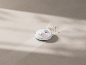 Aspirateur robot blanc nettoyant des débris sur un sol lisse.
