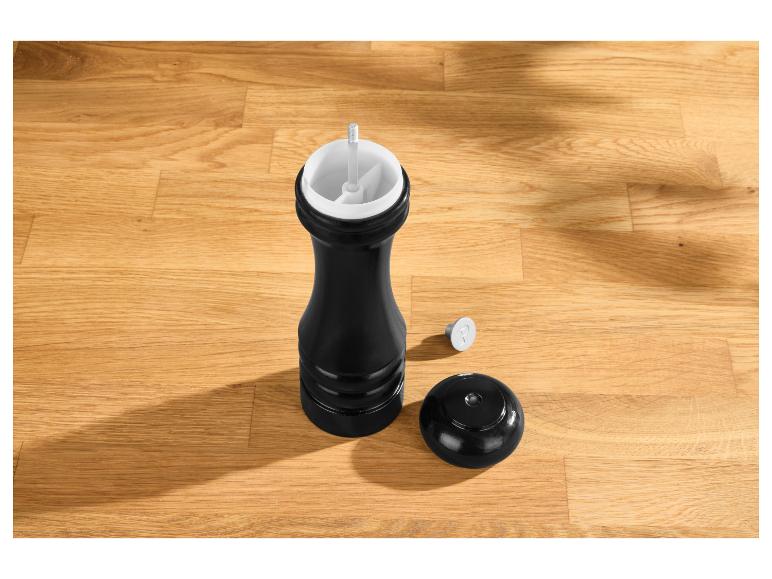 Moulin à poivre noir avec couvercle et un marquage 'P' sur une table en bois.