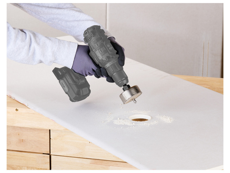 Une personne utilise une perceuse X20V Max avec une scie cloche pour percer un trou dans une surface en bois.