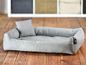 Un lit pour chien gris avec un coussin.