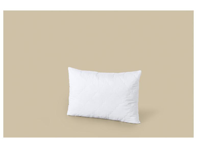 Oreiller blanc matelassé sur fond beige