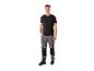 Homme en T-shirt noir et pantalon de travail gris avec empiècements noirs et chaussures de sécurité.