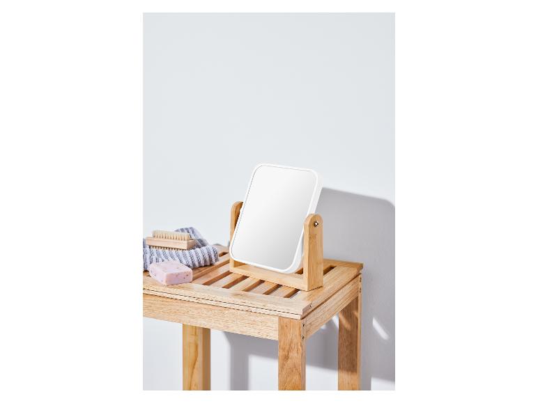 Un miroir blanc sur une étagère en bois avec du savon et une brosse.