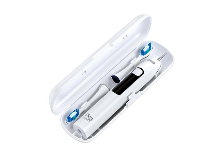 Brosse à dents électrique blanche et deux têtes dans un étui de voyage ouvert.