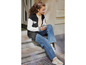 Une fille assise sur des marches portant une veste bomber, un jean et des baskets.