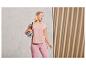 Une femme porte des vêtements de sport roses et tient un tapis de yoga.