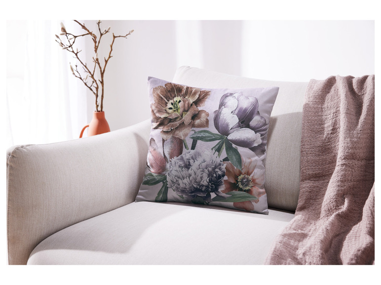 Un coussin à motif floral sur un canapé blanc.