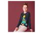 Une fille portant un pull de Noël avec un renne dans un sapin de Noël.