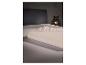 Drap-housse beige sur un lit, avec une lampe de chevet en arrière-plan