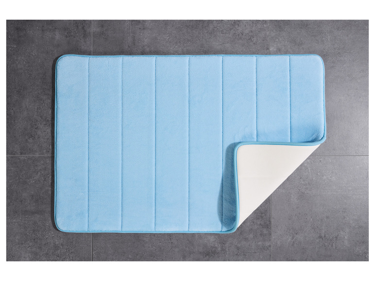 Un tapis de bain bleu clair avec un dessous antidérapant.