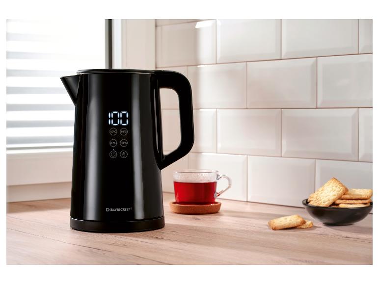 Bouilloire noire SilverCrest avec affichage numérique, tasse de thé et biscuits dans la cuisine.