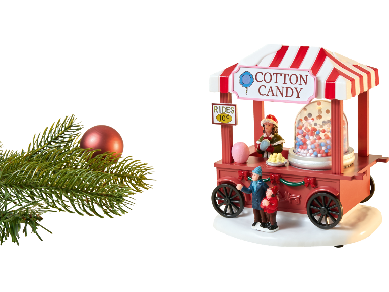 Sapin de Noël avec boule rouge et chariot en bois de barbe à papa avec figurines.