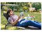 Un homme lisant un livre sur une chaise longue avec parasol dans le jardin.