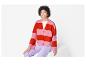 Une femme porte un pull rayé rose et rouge.