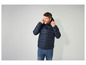 Un homme portant une veste matelassée bleue avec une capuche.