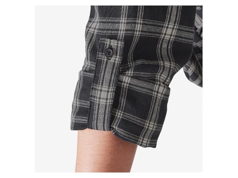 Détail du poignet d'une chemise à carreaux noirs et gris.