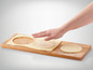 Une main qui presse une forme ronde de pâte sur une planche à découper en bois.