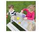 Deux enfants jouent avec une table de sable et d'eau dans un jardin.