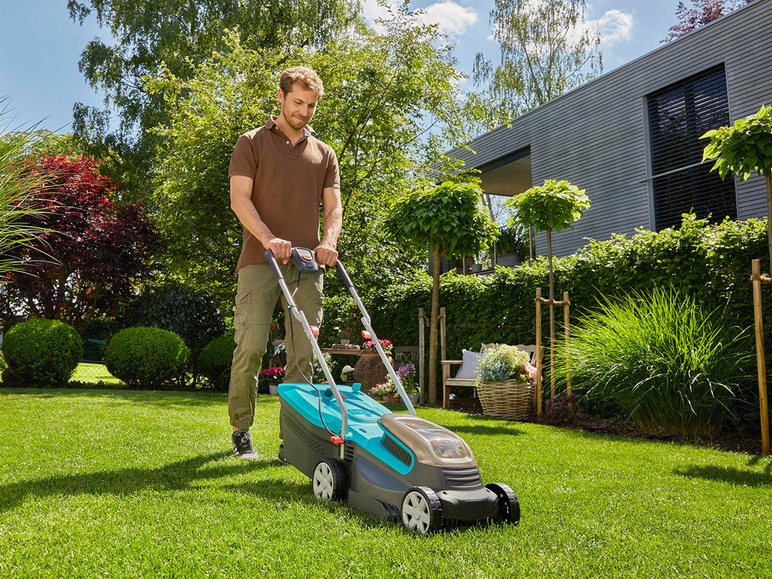 Un homme tond la pelouse avec une tondeuse à gazon électrique Bosch dans son jardin.