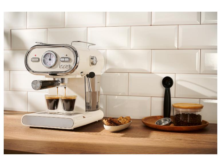 Une machine à expresso crème de style rétro préparant du café dans deux petits verres sur un comptoir en bois.