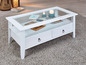 Table basse blanche avec plateau en verre, deux tiroirs et une étagère ouverte.