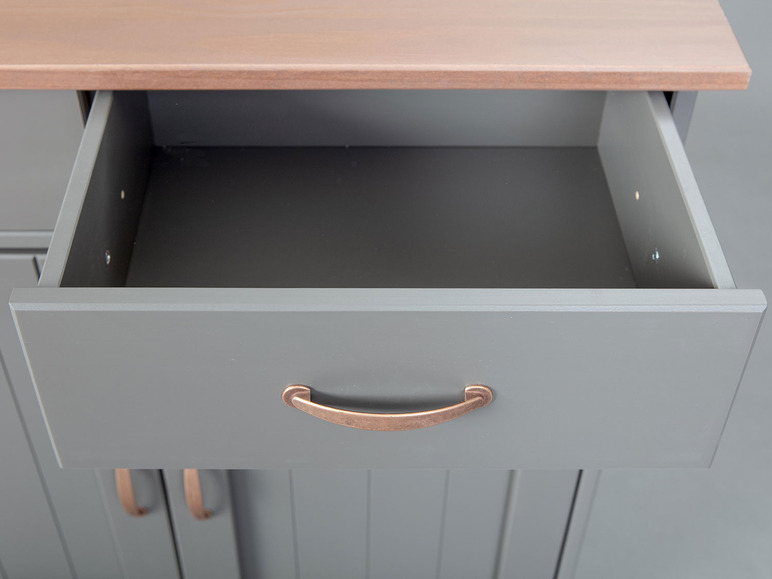 Un tiroir ouvert d'une commode grise avec des poignées en cuivre.