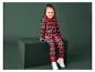 Une fille porte un pyjama de Noël rouge avec des rennes et des hommes en pain d'épices.