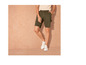 Un homme porte un short vert et des baskets blanches.