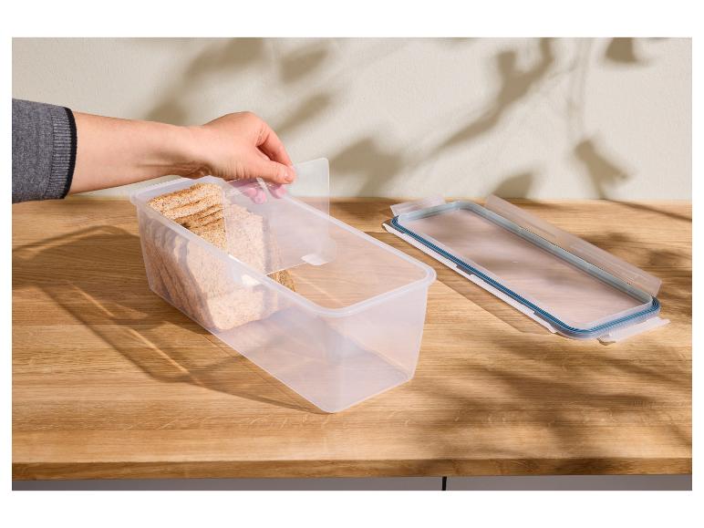 Main tenant un récipient alimentaire transparent avec du pain et un couvercle sur une table en bois.