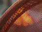Gros plan sur une chaise en maille orange avec un éclat ensoleillé qui la traverse.