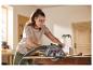 Une femme utilise la scie circulaire portative PARKSIDE PHKS 1350 E4 dans un atelier
