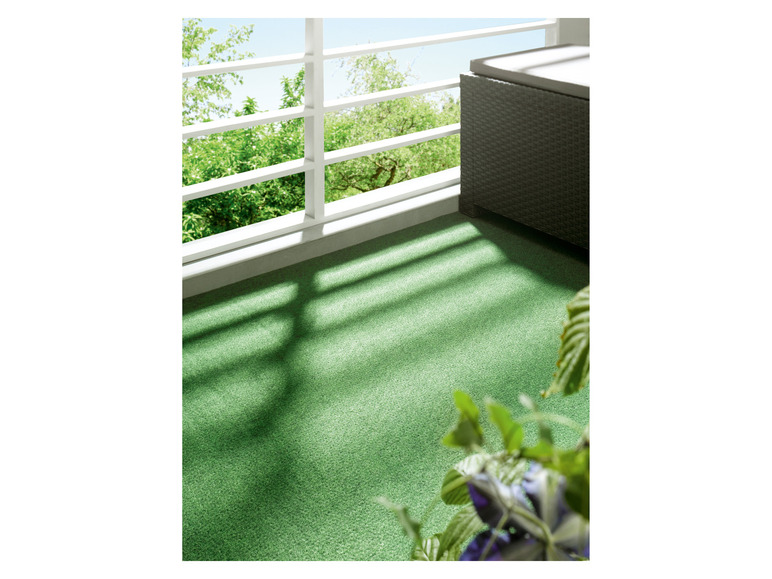 Un gazon artificiel vert avec un banc en osier à côté.