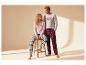 Couple en pyjamas à carreaux, elle assise, lui debout, se regardant.