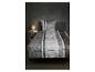 Chambre à coucher avec parure de lit rayée, table de chevet et lampe.