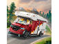Camping-car jouet avec figurines, roulant sur une route de montagne.