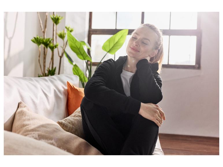 Femme détendue sur un canapé, vêtue d'une confortable tenue noire.