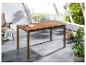 Une table de jardin en bois sur une terrasse avec des plantes vertes.